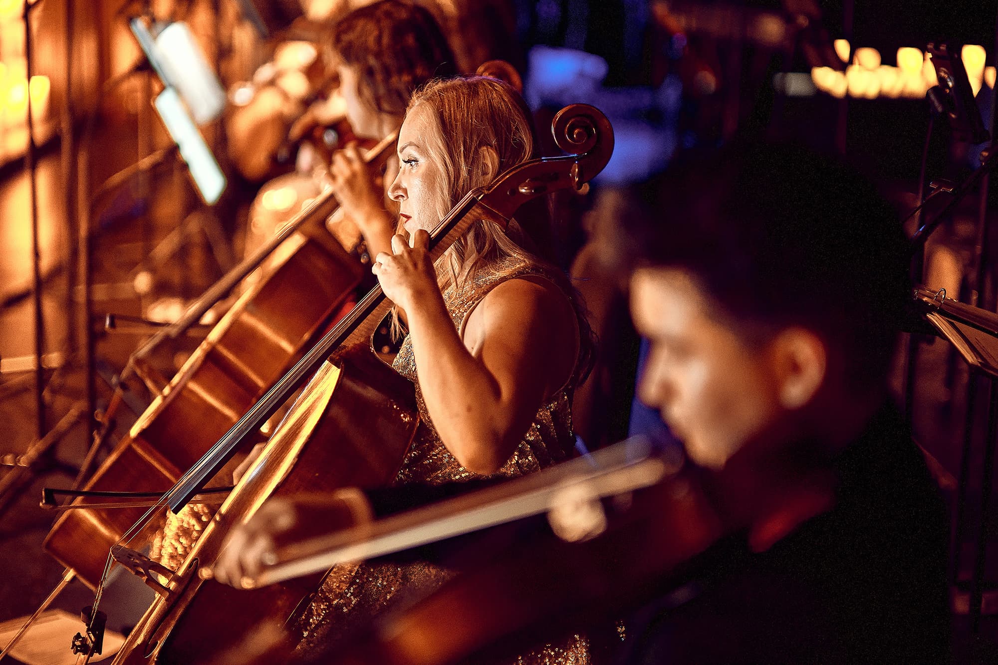 Close-up of cellists performing by candlelight